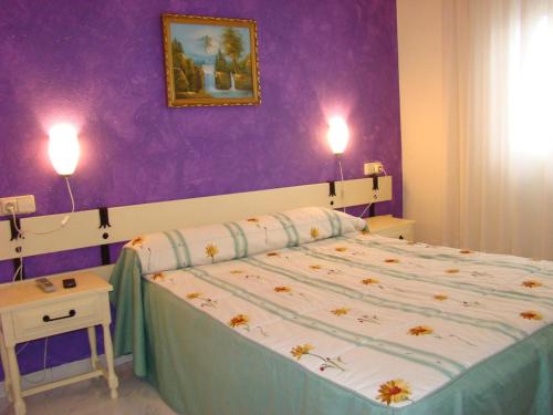 a bedroom with a bed with a purple wall at Pensión Mariaje in Celorio