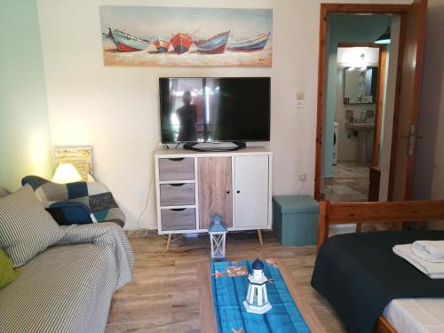a living room with a couch and a flat screen tv at Angel's Place by the Sea in Diakopto