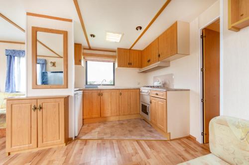 eine Küche mit Holzschränken und einem Fenster in der Unterkunft Domki u Beaty in Rewal