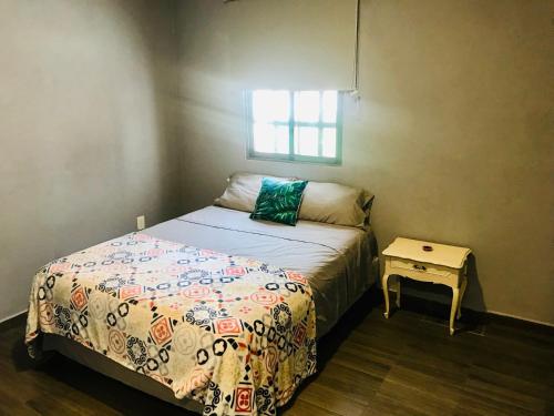 a small bedroom with a bed and a table at CASA MALIX Puerto Morelos in Puerto Morelos