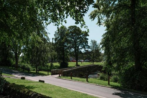 a road in a park with a bridge and trees at The Rectory Rooms, Studio 3 in Skipton