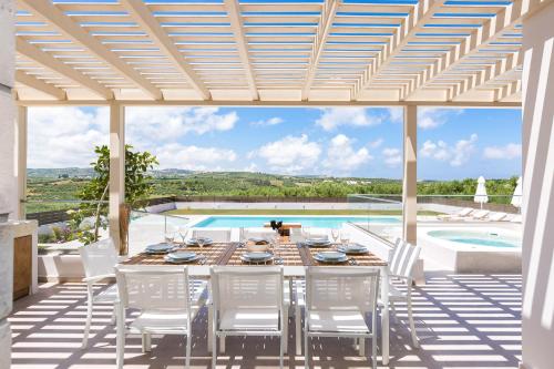 a patio with a table and chairs and a pool at Rosmerta Villa, with Private Pool 65 square meters, BBQ & Heated SpaWhirlpool, By ThinkVilla in Perama