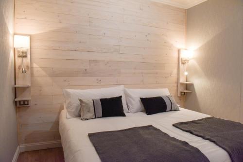 1 dormitorio con 1 cama grande y pared de madera en Hostal Boutique Puerta Roja, en Punta Arenas