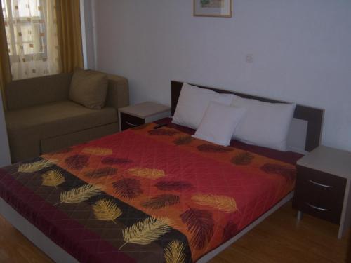 a bedroom with a bed with a red comforter and a couch at Apartmani Marija in Ohrid