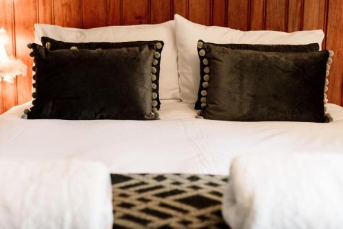 a bed with white sheets and black pillows at The Rectory Rooms, Studio 3 in Skipton