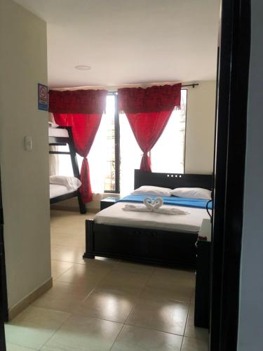 a bedroom with a bed and a window with red curtains at Hotel Dulces Sueños in Santa Rosa de Cabal