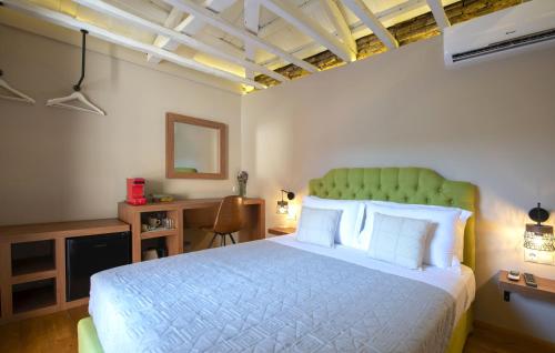 sypialnia z łóżkiem z zielonym zagłówkiem i biurkiem w obiekcie Metis Athens Suites w Atenach