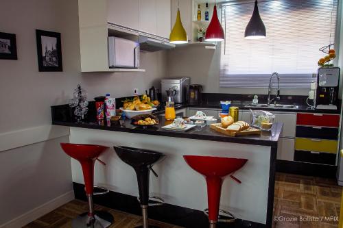 a kitchen with a counter with red bar stools at Bela Curitiba Hostel in Curitiba