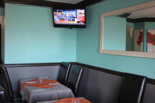 a dining room with two tables and a tv on the wall at Tiki Shores Inn & Suites in Penticton