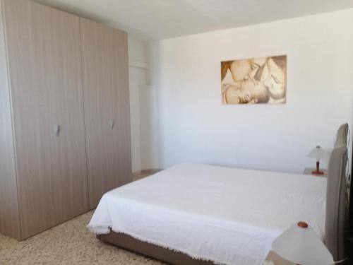 ピッツォルンゴにあるA Due Passi Dal Mareの白いベッドと壁に絵画が飾られたベッドルーム1室