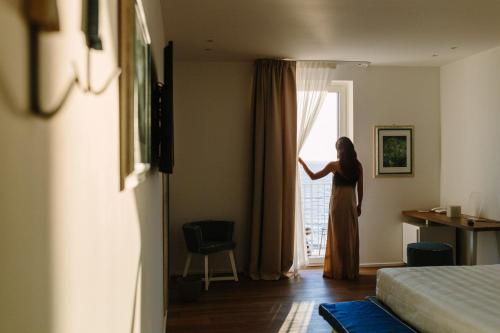 a woman looking out the window of a hotel room at NUMA HOTEL in Numana
