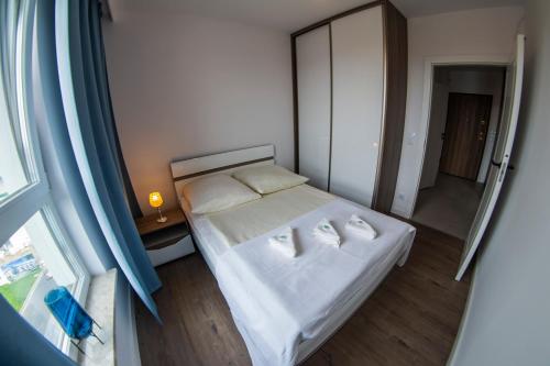 Dormitorio pequeño con cama con sábanas blancas y espejo en Morze-kwatery Apartament Bel Mare, en Międzyzdroje