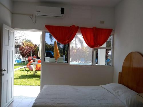 a bedroom with a bed and a window with red curtains at Hotel Villas del Rey in Chachalacas