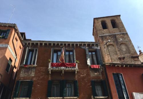 a building with a flag on a balcony with a tower at Alloggi Santa Sofia in Venice