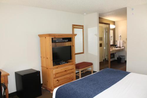 a bedroom with a bed and a dresser with a television at Baymont by Wyndham Yakima Riverfront in Yakima