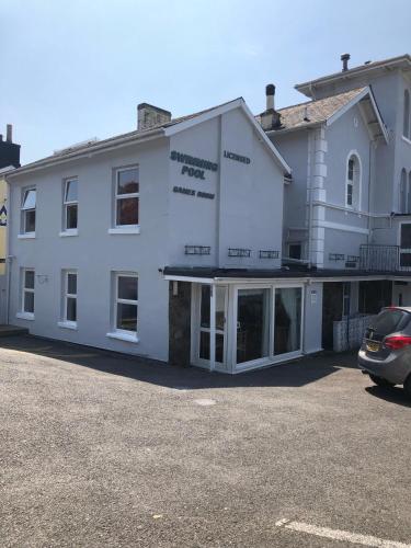a white building with a car parked in a parking lot at The Purple Tree Guest House in Torquay