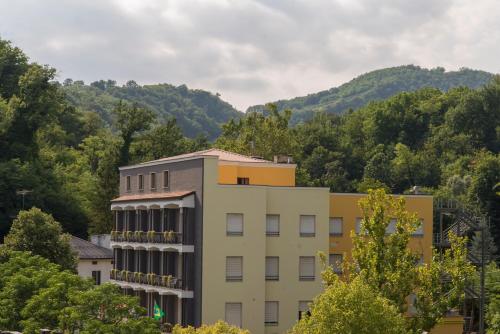 a building with trees and mountains in the background at Hotel Salus in Sant Andrea Bagni