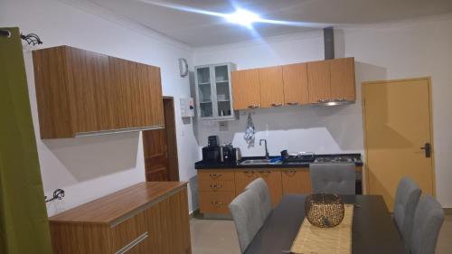 una cocina con armarios de madera y una mesa con sillas. en Ibex Heights, en Lusaka