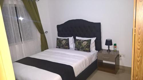 a bedroom with a bed with a black headboard and a window at Ibex Heights in Lusaka