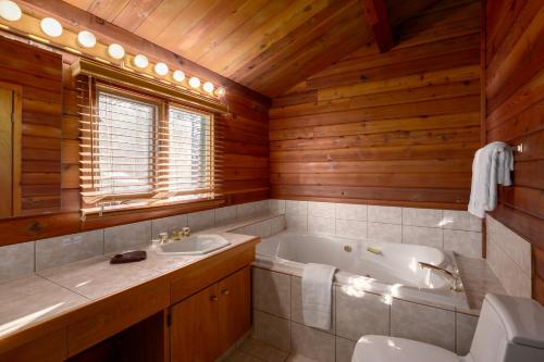 y baño con bañera, aseo y lavamanos. en Creekside Cabin en Fairmont Hot Springs