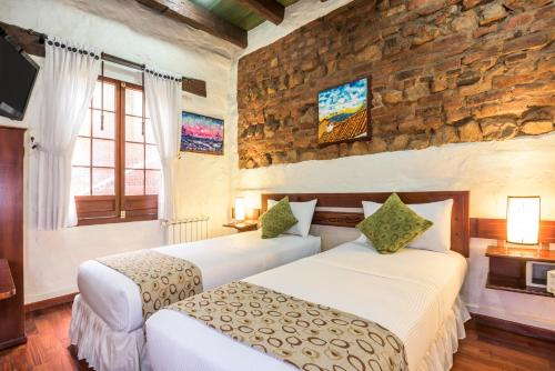 a bedroom with two beds and a stone wall at Hotel Muisca in Bogotá