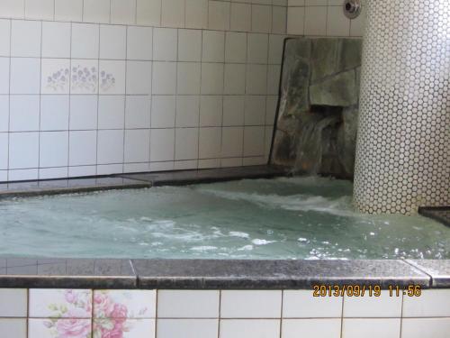 a bath tub filled with water in a bathroom at Takaraya in Kotohira