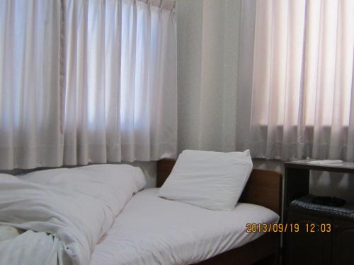 a bed with white pillows in front of a window at Takaraya in Kotohira