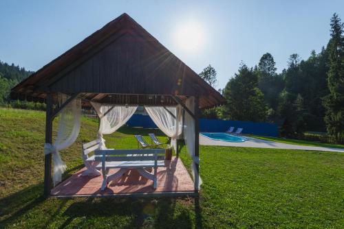 a gazebo with a bench in the grass at Agroturystyka u Chlebków in Ochotnica Górna