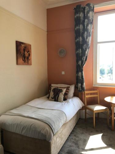 a small bedroom with a bed with a window at The Purple Tree Guest House in Torquay