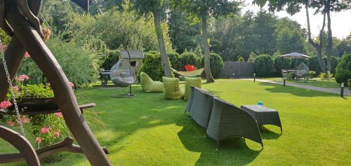 a garden with chairs and a hammock in the grass at Rasos Vila in Palanga