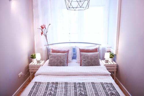 a bedroom with a bed with pink pillows and a window at Chill & Explore by Cooee Apartments in Warsaw