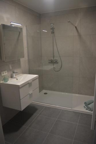 a white bathroom with a sink and a shower at Residentie Capri in Middelkerke