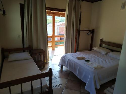 a bedroom with two beds and a door to a porch at Estalagem São Gonçalo in Tarituba