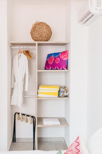 a closet with white shelves and a basket and towels at Great Villas estudios & residences - THE KAHLO in Playa del Carmen