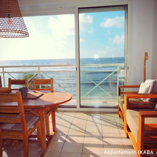 a dining room with a table and a view of the ocean at Appartement sur la plage, avec vue panoramique sur le lagon - IKABA in Saint-François