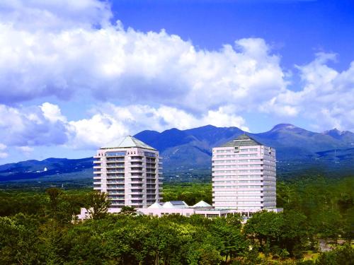 two tall white buildings with mountains in the background at Hotel Epinard Nasu in Nasu