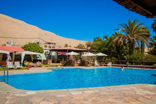 - une piscine avec des chaises et des parasols dans un complexe dans l'établissement DM Hoteles Mossone - Ica, à Ica