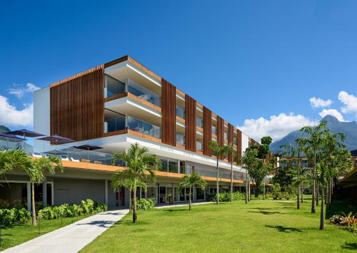 a building with palm trees in front of it at Hotel Fasano Angra dos Reis in Angra dos Reis