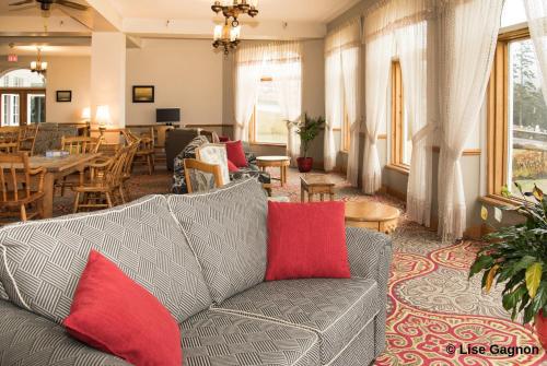a living room with a gray couch and red pillows at Hotel Tadoussac in Tadoussac