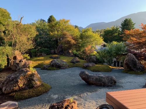 a garden with rocks and trees and mountains in the background at Onsen & Garden -Asante Inn- in Hakone