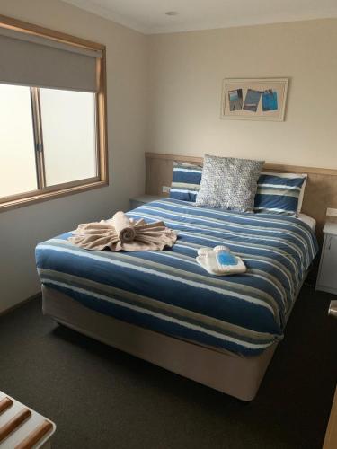 a bedroom with a large bed with blue and white sheets at NRMA Tathra Beachfront Holiday Park in Tathra
