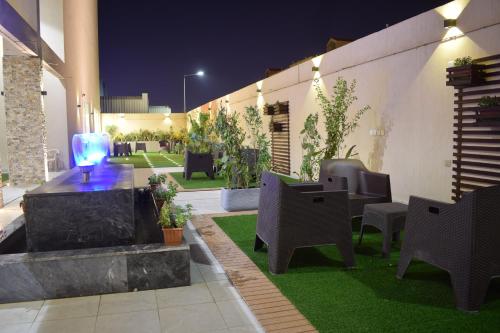 un patio con sillas y una mesa y un jardín por la noche en AlMogheeb units en Riad