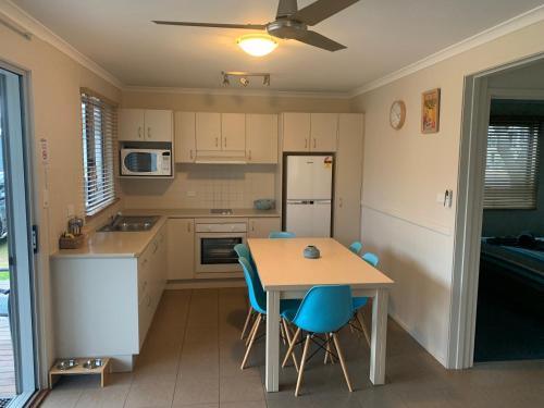 a kitchen with a table and chairs and a refrigerator at NRMA Tathra Beachfront Holiday Park in Tathra
