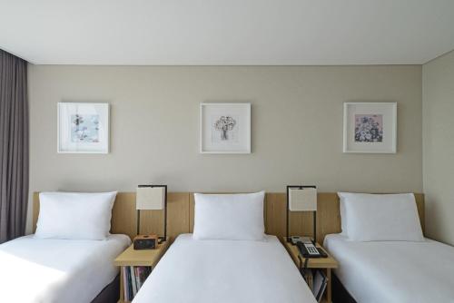 two beds in a hotel room with white sheets at Harbor Park Hotel in Incheon