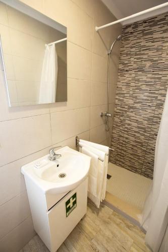 a white bathroom with a sink and a shower at 3stúdio in Peniche
