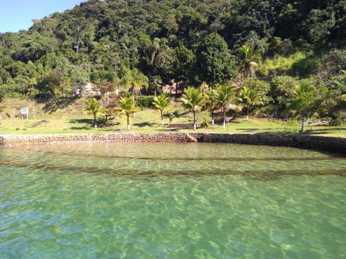 a body of water with palm trees and a mountain at Vale do Pontal Angra Suites in Angra dos Reis