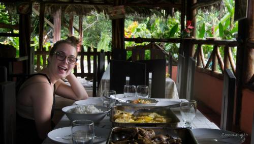 a woman sitting at a table with food on it at Oro y Luna Lodge in Carlos Julio Arosemena Tola