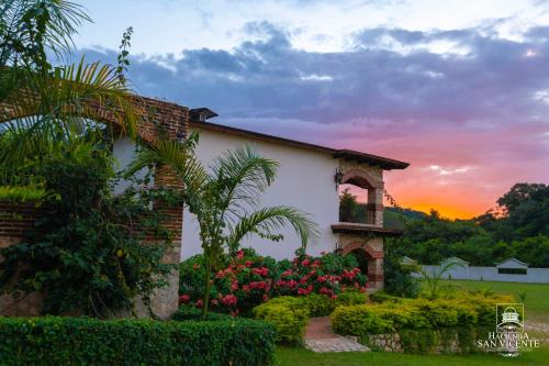 a house with flowers and a sunset in the background at Hacienda San Vicente in Flores
