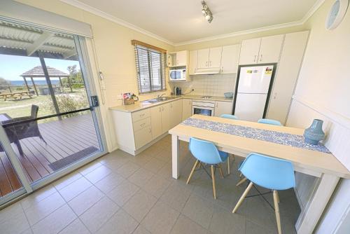 a kitchen with a wooden table and blue chairs at NRMA Tathra Beachfront Holiday Park in Tathra