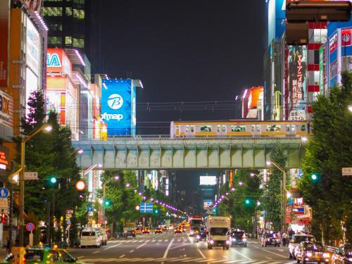 a busy city street at night with a train on a bridge at Super Hotel Premier Akihabara in Tokyo